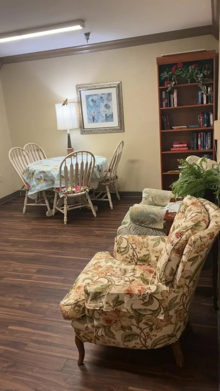 A common room at Vivo Healthcare Gandy, with a dining table, bookshelves and armchairs