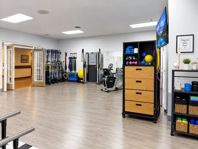 A corner of the therapy gym at Vivo Healthcare Gandy, with a recumbent stepper and equipment shelving